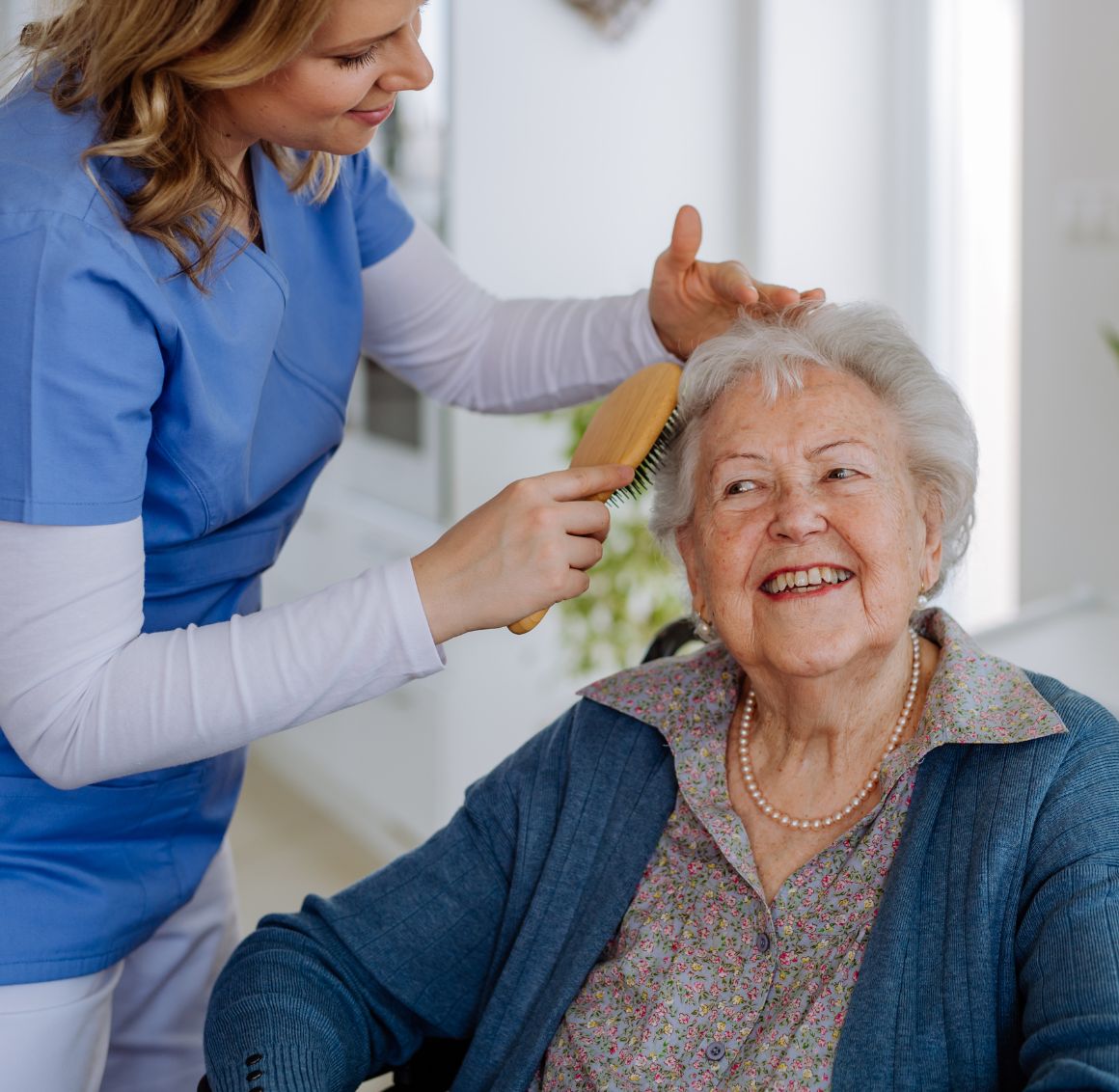 Caregiver brushing hair of an elderly woman